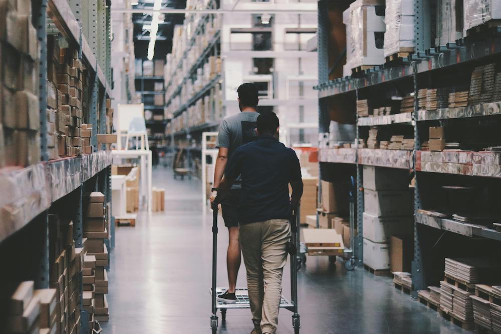 Men pushing a cart in a warehouse.